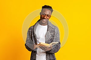 Smiling young african guy reading book for education