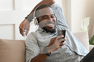 Smiling young african man wearing headphones listen to mobile music