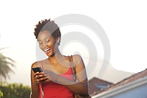 Smiling young african reading text message on her mobile phone