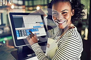 Smiling young waitress using a restaurant point of sale terminal photo