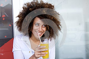 Smiling young african woman drinking juice at outdoor cafe