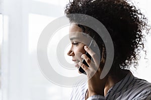 Smiling young african woman holding mobile phone close to ear