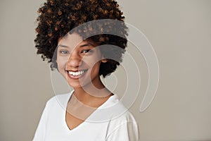 Smiling young African woman standing against a gray background