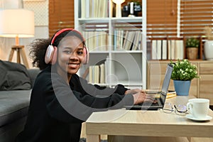 Smiling young African woman watching learning online in virtual classroom on laptop. E-learning education concept