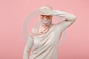 Smiling young arabian muslim girl in hijab light clothes posing isolated on pink wall background studio portrait. People