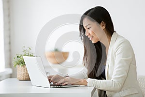 Smiling young asian businesswoman using computer working online photo