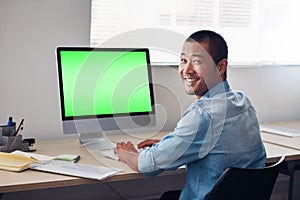 Smiling young Asian designer at work on an office computer