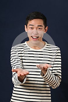 Smiling young Asian man gesturing with two hands