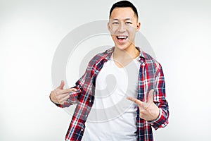Smiling young Asian man in a shirt wide open shows blank space on his white T-shirt on an isolated white studio
