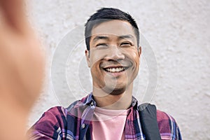 Smiling young Asian man taking a selfie in the city