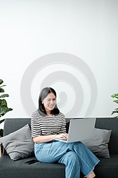 Smiling young asian teen girl video calling on laptop. Happy mixed race pretty woman student looking at computer screen