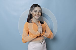 Smiling young Asian woman gesturing greeting or namaste isolated over white background