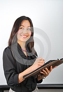 Smiling young Asian woman making notes