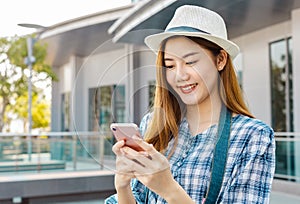 Smiling young Asian woman with shopping colour bags over mall background. using a smart phone shopping online  and smiling while