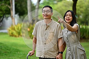 Smiling young Asian woman showing something interesting to her senior father. Family, wellness and health care