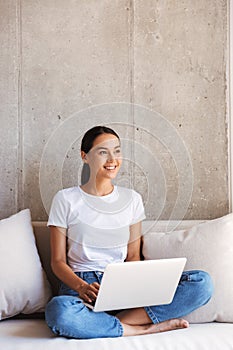 Smiling young asian woman using laptop computer