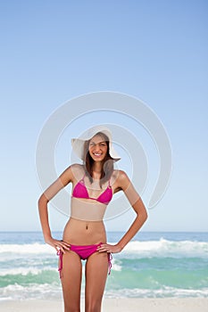 Smiling young attractive woman placing her hands on hips in front of the sea