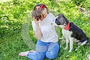 Smiling young attractive woman playing with cute puppy dog border collie in summer garden or city park outdoor