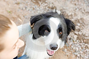 Smiling young attractive woman playing with cute puppy dog border collie on summer outdoor background. Girl holding