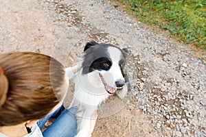 Smiling young attractive woman playing with cute puppy dog border collie on summer outdoor background. Girl holding