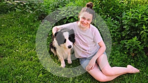 Smiling young attractive woman stroking playing with cute puppy dog border collie on summer outdoor background. Owner