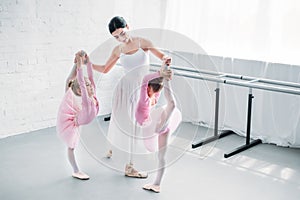 smiling young ballet teacher exercising with kids