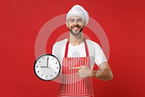 Smiling young bearded male chef cook or baker man in striped apron white t-shirt toque chefs hat isolated on red