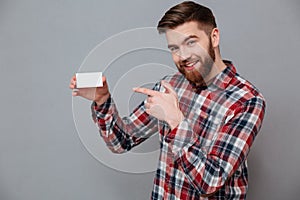 Smiling young bearded man holding copyspace business card