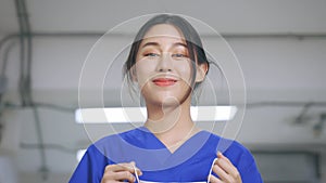 Smiling young and beautiful Asian medical nurse in uniform at hospital prepared to wear a face mask