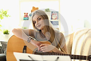 Smiling young beautiful girl playing guitar at home