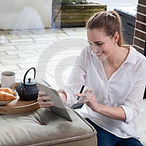 Smiling young beautiful woman enjoying ecommerce from home tablet