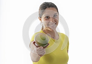 A smiling young beautiful woman offering an out of focus mango at the camera. Healthy food concept