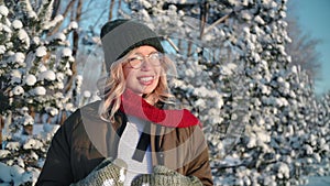 Smiling young beautiful woman relaxing having fun posing at sunny winter forest with snowy spruce