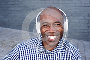 Smiling young black guy listening to music with headphones