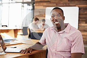 Smiling young black man in creative office looking to camera