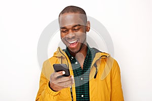 Smiling young black man looking at mobile phone against isolated white background