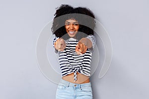 Smiling young black woman pointing fingers against gray background