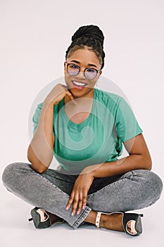 Smiling young black woman sitting on the floor with her hand on the chin