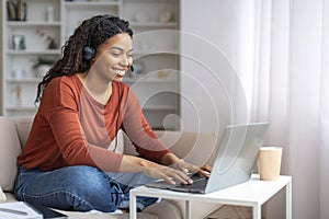 Smiling Young Black Woman Wearing Headset Using Laptop Computer At Home