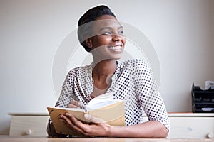 Smiling young black woman writing in journal at home