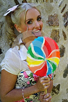 Smiling young blond woman with big lollipop