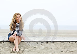 Smiling young blond woman sitting at the beach