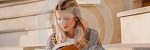 Smiling young blonde casual woman reading book