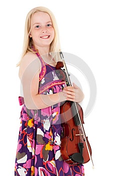 Smiling young blonde girl in a flowery dress poses with violin on a white studio background