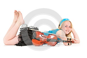 Smiling young blonde girl lay down posing with violin and bow on a white studio background