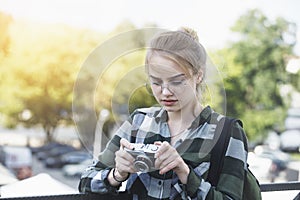 Smiling young blonde woman holding old retro film camera and taking pictures, copy space, amateur photographer, sunny summer