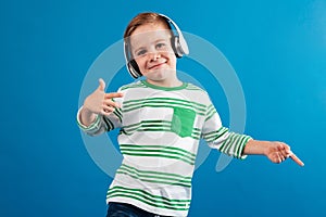 Smiling young boy listening music and dancing