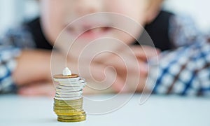 Smiling young boy with missing front tooth. Pile of coins with a baby tooth on top.