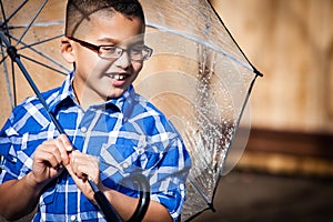 Smiling young boy in the rain with umbrella