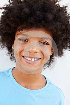 Smiling Young Boy Standing Outdoors Against White Wall